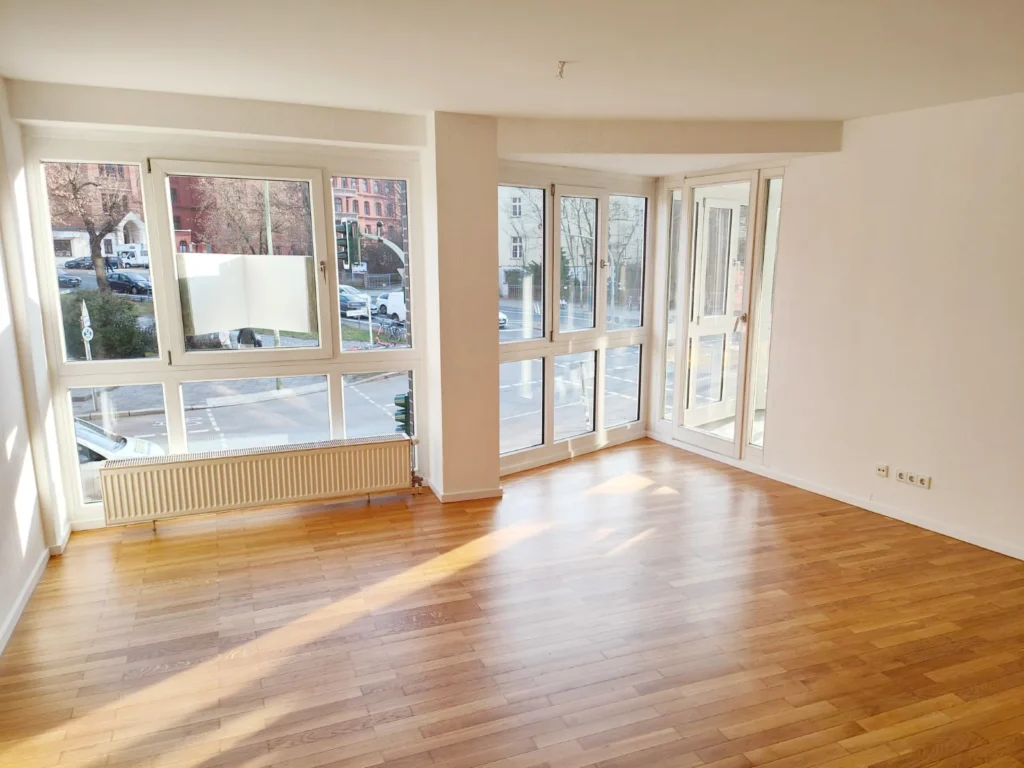 Fertiggestellter Raum mit großer Fensterfront mit weißen Wänden und einem Holzboden aus anderer Perspektive